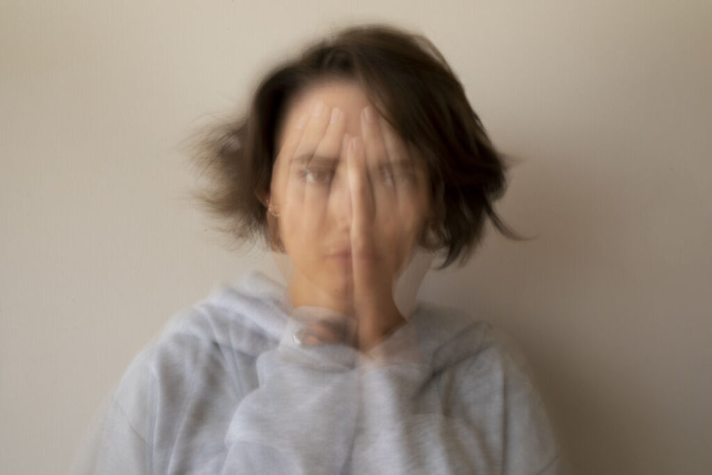 Blurry depiction of a woman covering her face, evoking a sense of anonymity or emotional vulnerability.